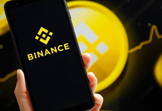Ukraine, Odessa – October, 9 2021: Hand holding mobile with Binance app running at smartphone screen with Binance logo at background. Binance is cryptocurrency exchange and trading platform