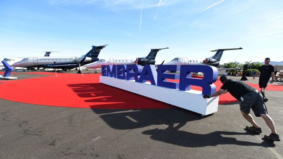 Funcionários ajeitam letreiro da Embraer durante exposição em Las Vegas - REUTERS/David Becker